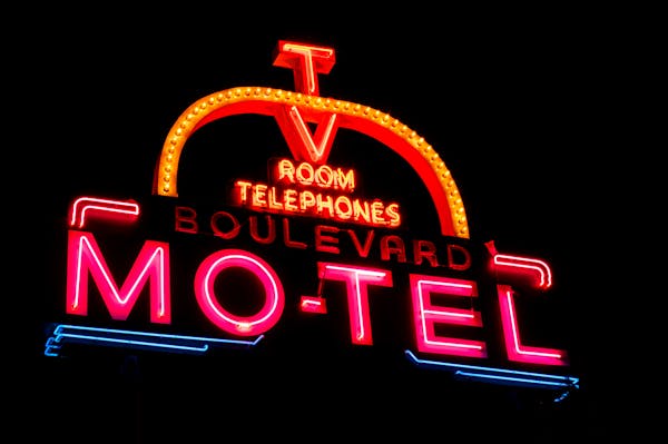 Illuminated neon sign of Boulevard Motel glowing brightly against night sky, urban setting.