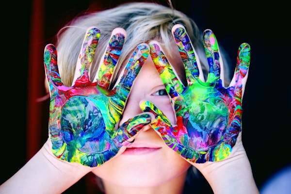 Vibrant close-up of a child's hands covered in colorful paint, expressing creativity and fun.